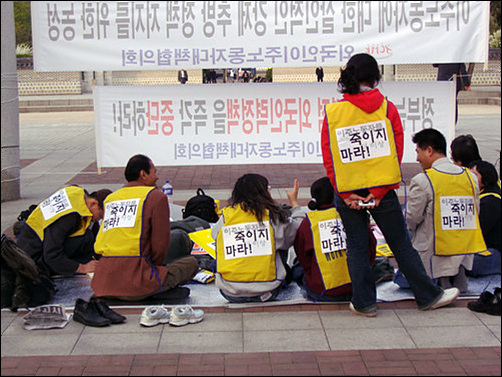 농성단 등 뒤에 붙인 '이주노동자를 더 이상 죽이지 마라' 